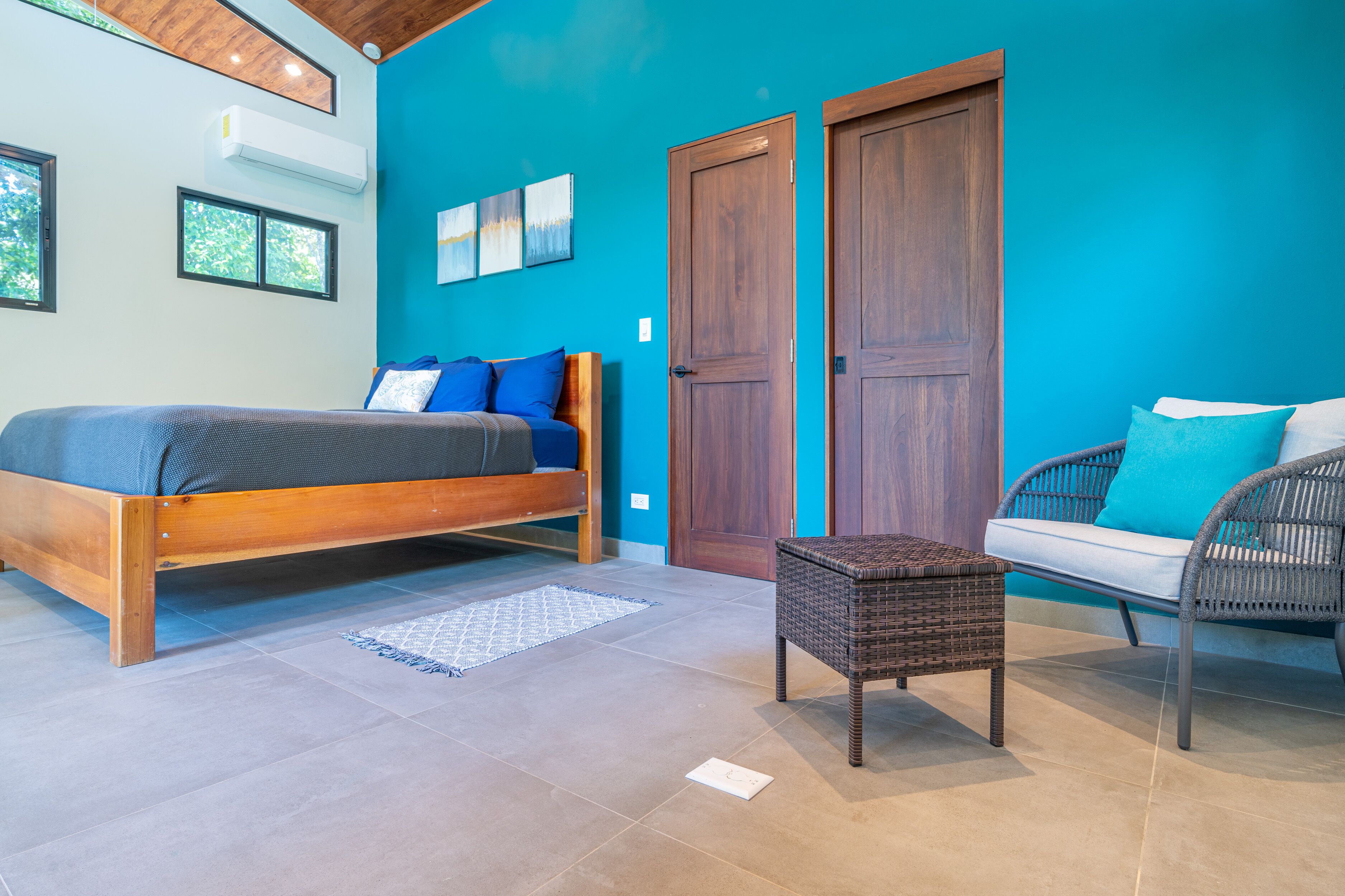 Un dormitorio con una cama, un sillón de mimbre y un sofá.