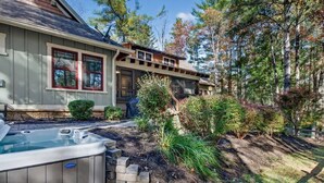 Une maison avec un jacuzzi, un mur en pierre et une terrasse en bois.