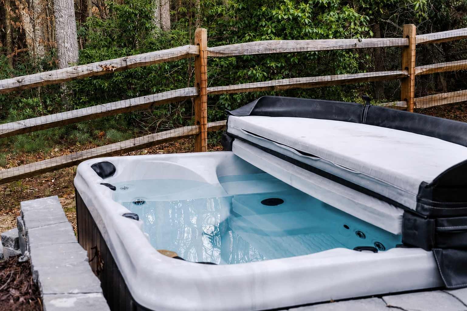 Un bain à remous avec une clôture en bois en arrière-plan.