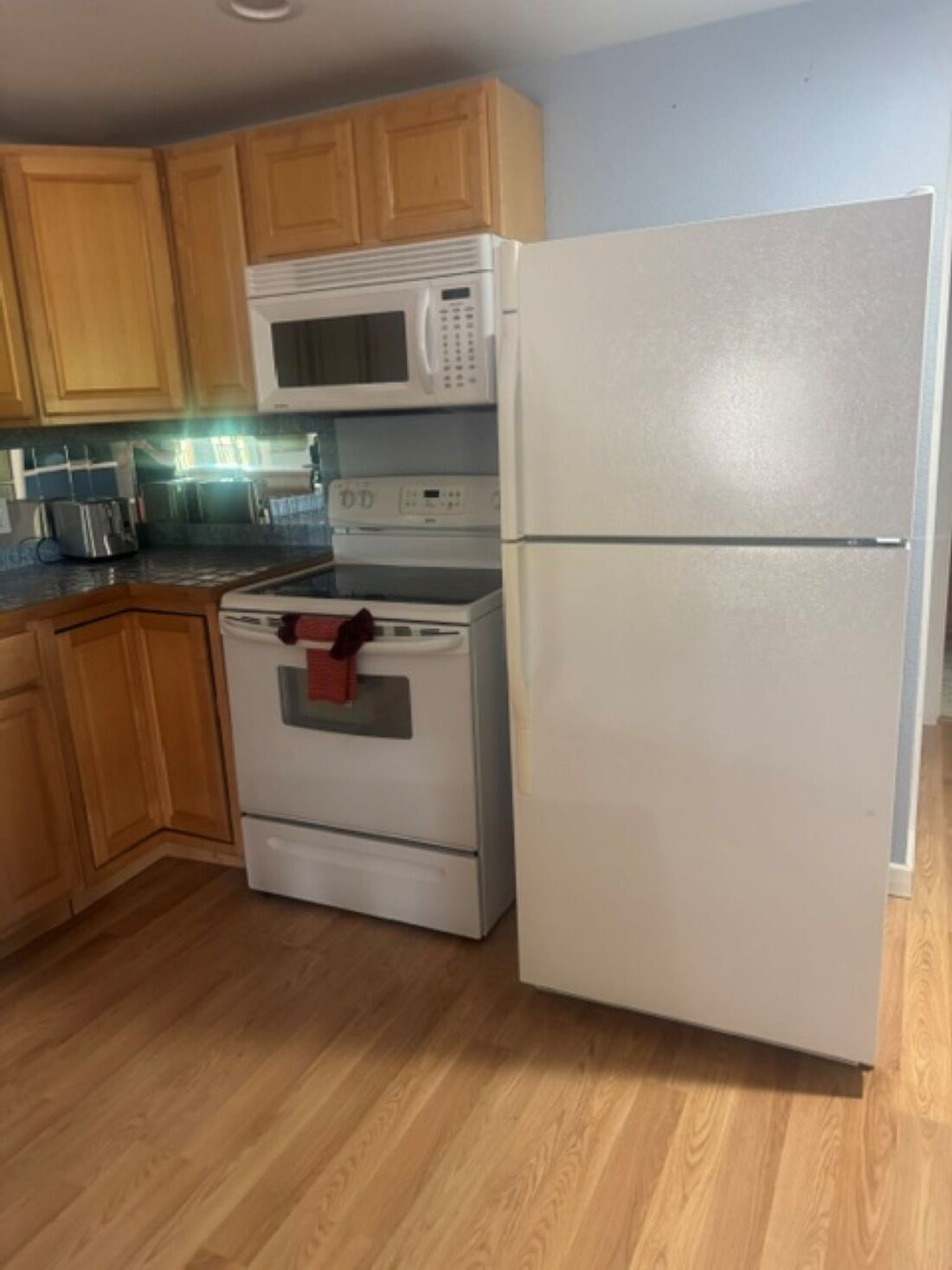 Una cocina con armarios de madera, un microondas, una estufa y un refrigerador.
