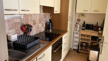 Een koelkast, een oven, een broodrooster, kookgerei, borden en bestek