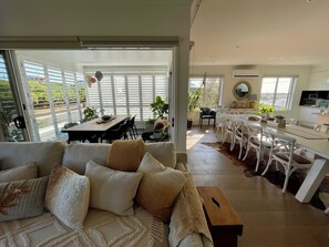 A spacious living area with a sofa, dining table, and kitchen area. - Luxury At The Lookout - Park and Beach Across The Road! (Ocean Grove)