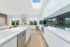 A modern kitchen with a central island, large windows, and a skylight. - Luxury At The Lookout - Park and Beach Across The Road! (Ocean Grove)
