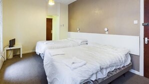 A hotel room with two beds, a small bedside table with a TV, and a light fixture on the ceiling. - Jini Hotel (Blackpool)