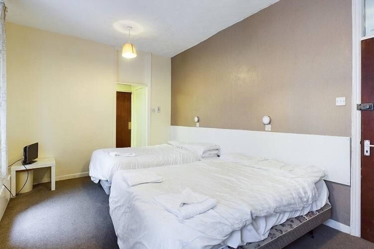 A hotel room with two beds, a small bedside table with a TV, and a light fixture on the ceiling.