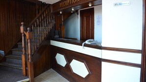 A reception area with a wooden staircase, a reception desk, and a telephone. - Jini Hotel (Blackpool)