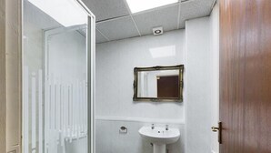 Une salle de bain avec une douche à parois de verre, un lavabo blanc et des toilettes.