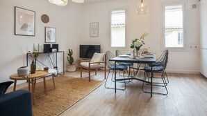 A modern dining area with a wooden table, chairs, and a woven rug. - Loft L'Escale - 3 étoiles - Welkeys (La Ciotat)