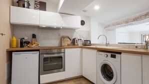 A compact kitchen with a dishwasher, oven, and washing machine. - Suite Mugel - 3 étoiles - Welkeys (La Ciotat)