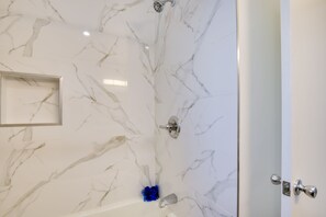 Een badkamer met marmeren wanden, een douche en een deur met zilveren handvat.