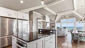 A modern kitchen with stainless steel appliances, a large island, and a view of the ocean. - Coastal LunaSea: Oceanfront, Pool, Elevator OBX (Corolla)