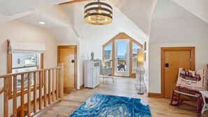 A spacious loft with a high ceiling, a wooden staircase, a large bay window, and a view of the ocean. - Cedar Sandcastle*semi-oceanfront*Hot Tub*Foosball (Nags Head)
