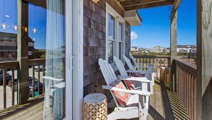 A wooden deck with white chairs and a small table, overlooking a residential area. - Cedar Sandcastle*semi-oceanfront*Hot Tub*Foosball (Nags Head)