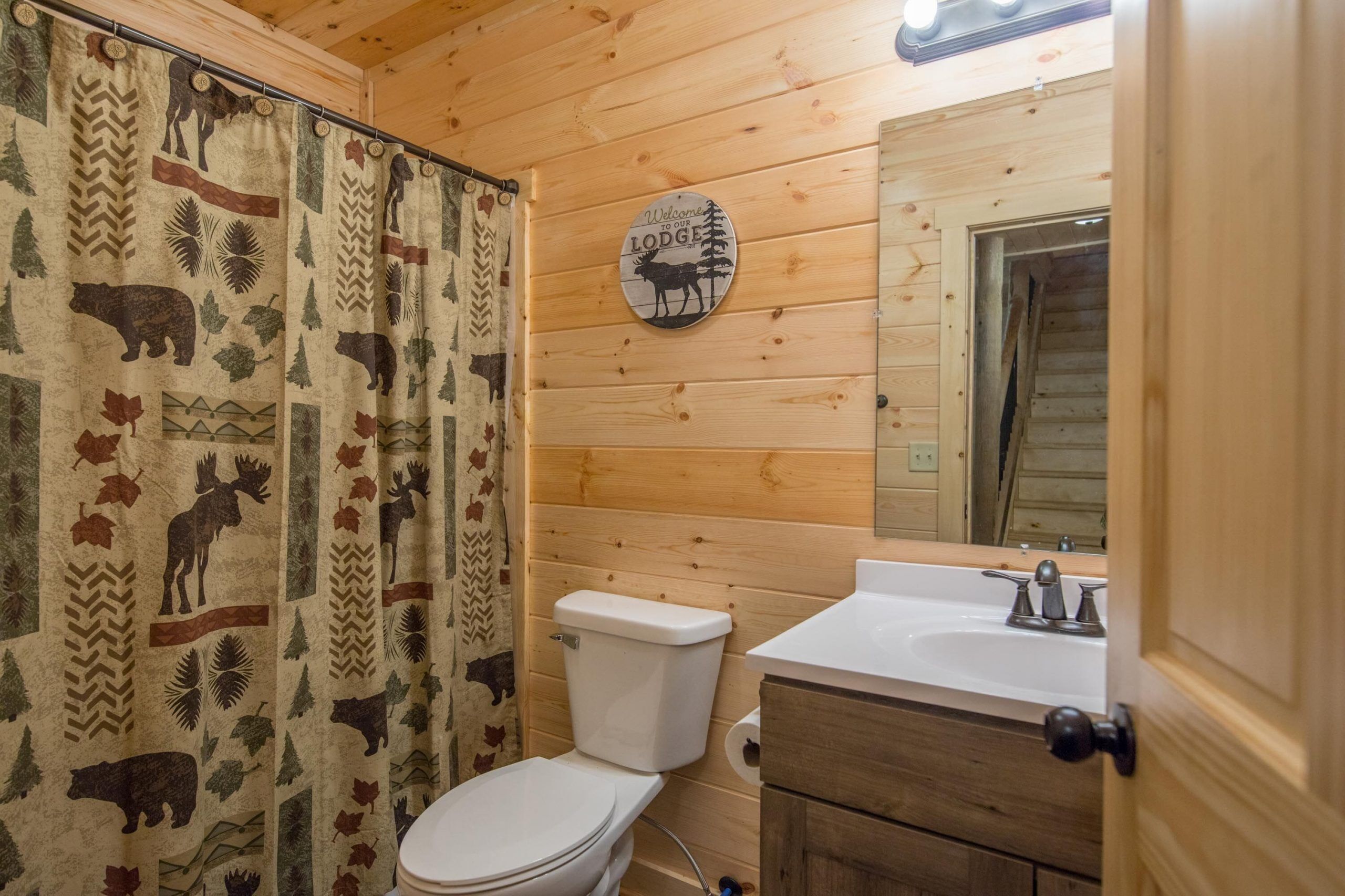 A wooden-paneled bathroom with a toilet, sink, and a mirror.