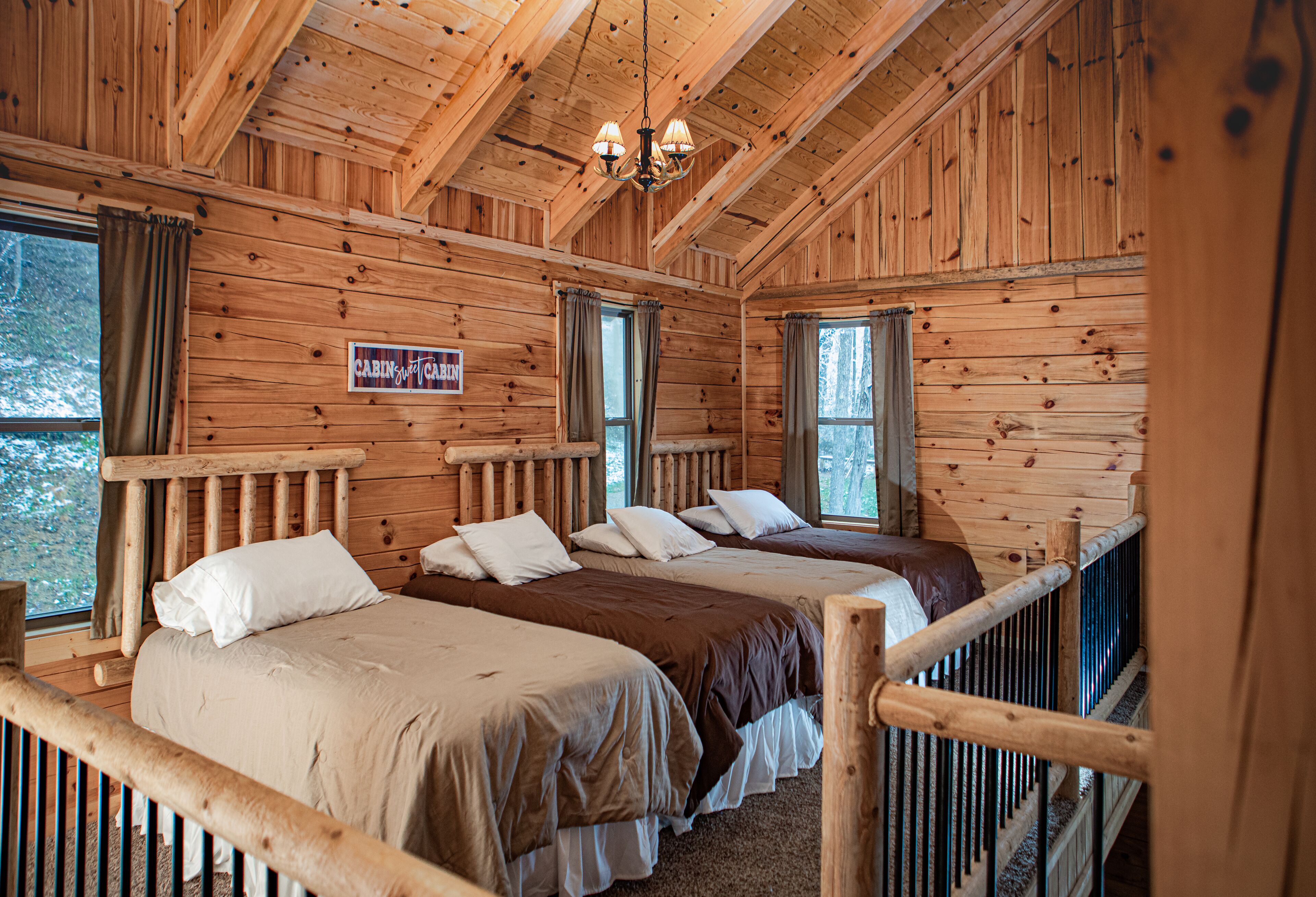 Ein Blockhaus-Zimmer mit zwei Betten und Holzwänden, mit einem Schild, auf dem "Cabin Suite" steht.