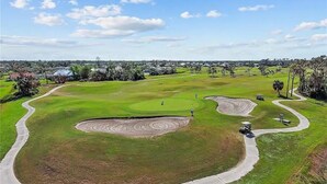 Un parcours de golf avec des allées bien entretenues, des bunkers de sable et un ciel dégagé.