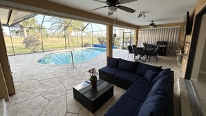 Un patio couvert avec une piscine, du mobilier d’extérieur et un ventilateur de plafond.