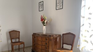 Una habitación con dos sillas de madera, un aparador de madera y un florero con flores.