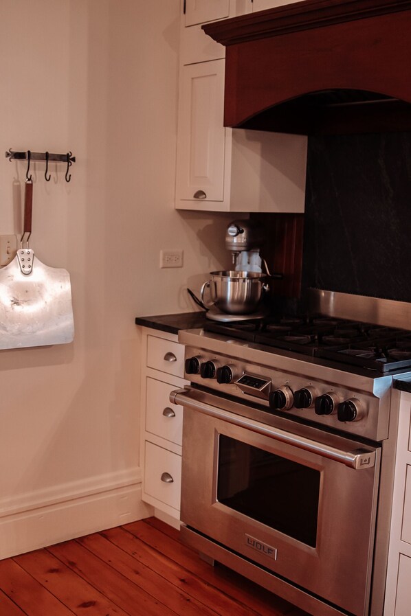 A kitchen with a stainless steel oven, a gas stove, and a hanging pot holder.