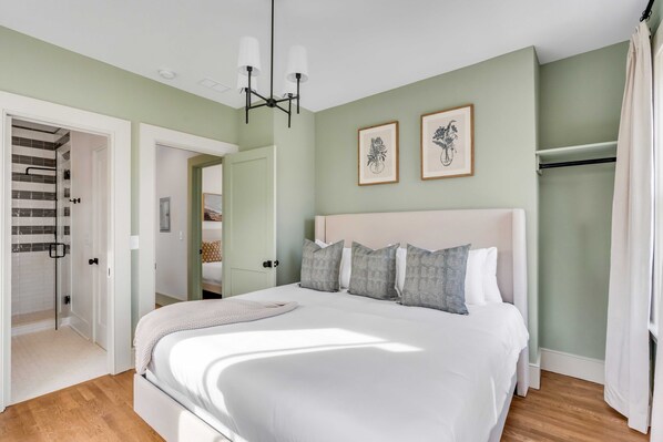 Une chambre avec un grand lit, un dressing et un espace douche.