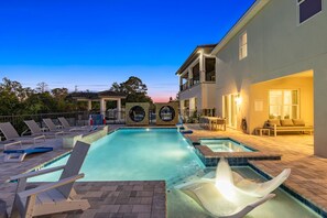 A pool area with lounge chairs, a hot tub, and a covered seating area.