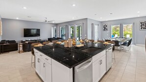 Una cucina moderna con una grande isola, mobili bianchi e un piano di lavoro nero.