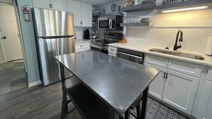 Een moderne keuken met roestvrijstalen apparatuur, witte kasten en een centraal eiland.