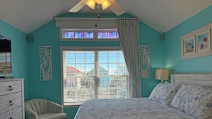 A bedroom with a bed, a chair, a dresser, a window with curtains, and a ceiling fan. - Surfside Breezes - Second Row in Surfside Beach (Surfside Beach)