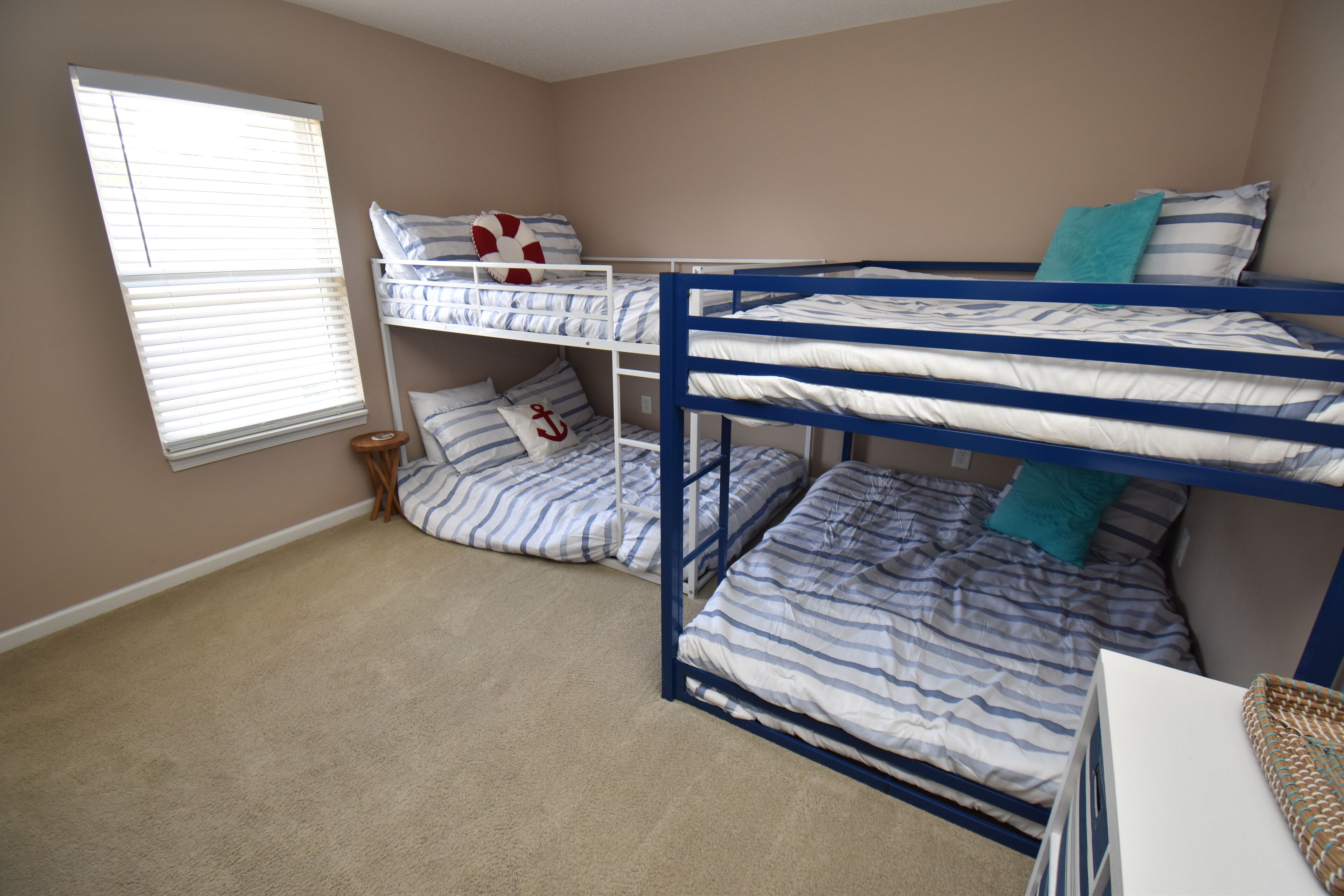 A bunk bed room with striped bedding and a window with blinds.