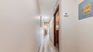 Un pasillo con suelo de madera, una puerta a la derecha y un cartel de 'No Fumar' en la pared.