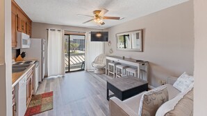 Un espacio habitable compacto con kitchenette, zona de comedor, sofá y ventilador de techo.