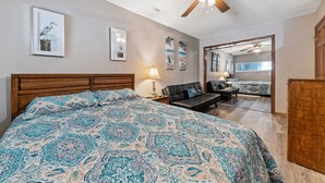 Un dormitorio con una cama grande, un cabecero de madera, un ventilador de techo y un espejo que refleja la habitación.