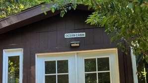 Una cabaña de madera con un letrero que dice "OCEAN CABIN", una escalera de madera y una barandilla de metal.