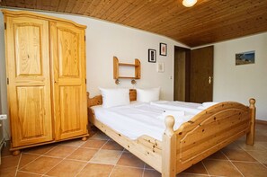 A wooden bed with a headboard, a wardrobe, and a wall-mounted shelf.