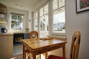 A kitchen with a wooden table, chairs, a coffee maker, and a stove. - Die Ferienwohnung Nr. 01 in der Villa am Sonnenhang - Villa am Sonnenhang (Göhren)