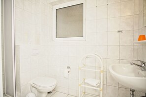 Une petite salle de bain avec des toilettes, un lavabo et une fenêtre.