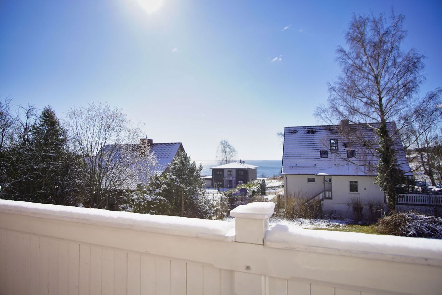 A residential area with houses, a clear sky, and a view of the sea.