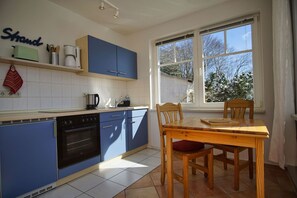 Eine Küche mit blauen Schränken, einem Holztisch und einem Fenster mit Blick auf schneebedeckte Bäume.