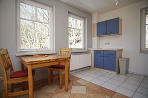 A kitchen with a wooden table and chairs, blue cabinets, and a radiator. - Vacation apartment in a quiet location, with sea view - Villa am Sonnenhang FeWo 03 - (Göhren)
