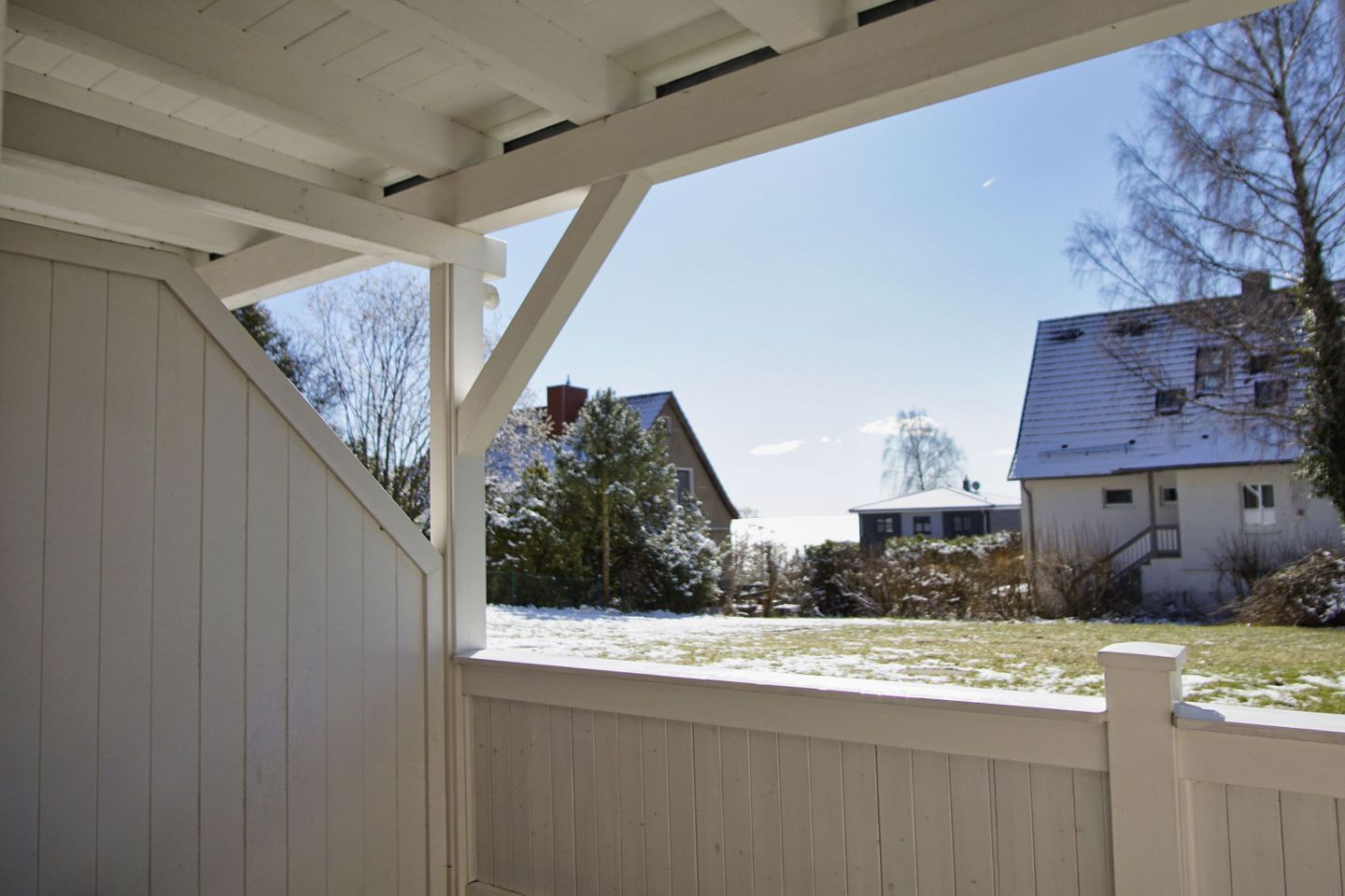 Eine überdachte Veranda mit Blick auf eine Wohngegend, einschließlich Häusern und Bäumen.
