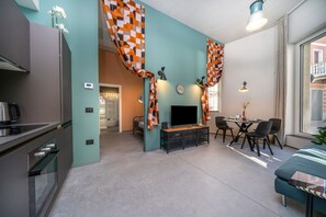 A compact living space with a kitchenette, a dining area, and a TV. - GuestHost - Udine Good Vibes (This Way) Apartment (Udine)