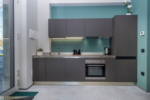 A modern kitchen with grey cabinets, a built-in oven, and a coffee maker. - GuestHost - Udine Good Vibes (This Way) Apartment (Udine)