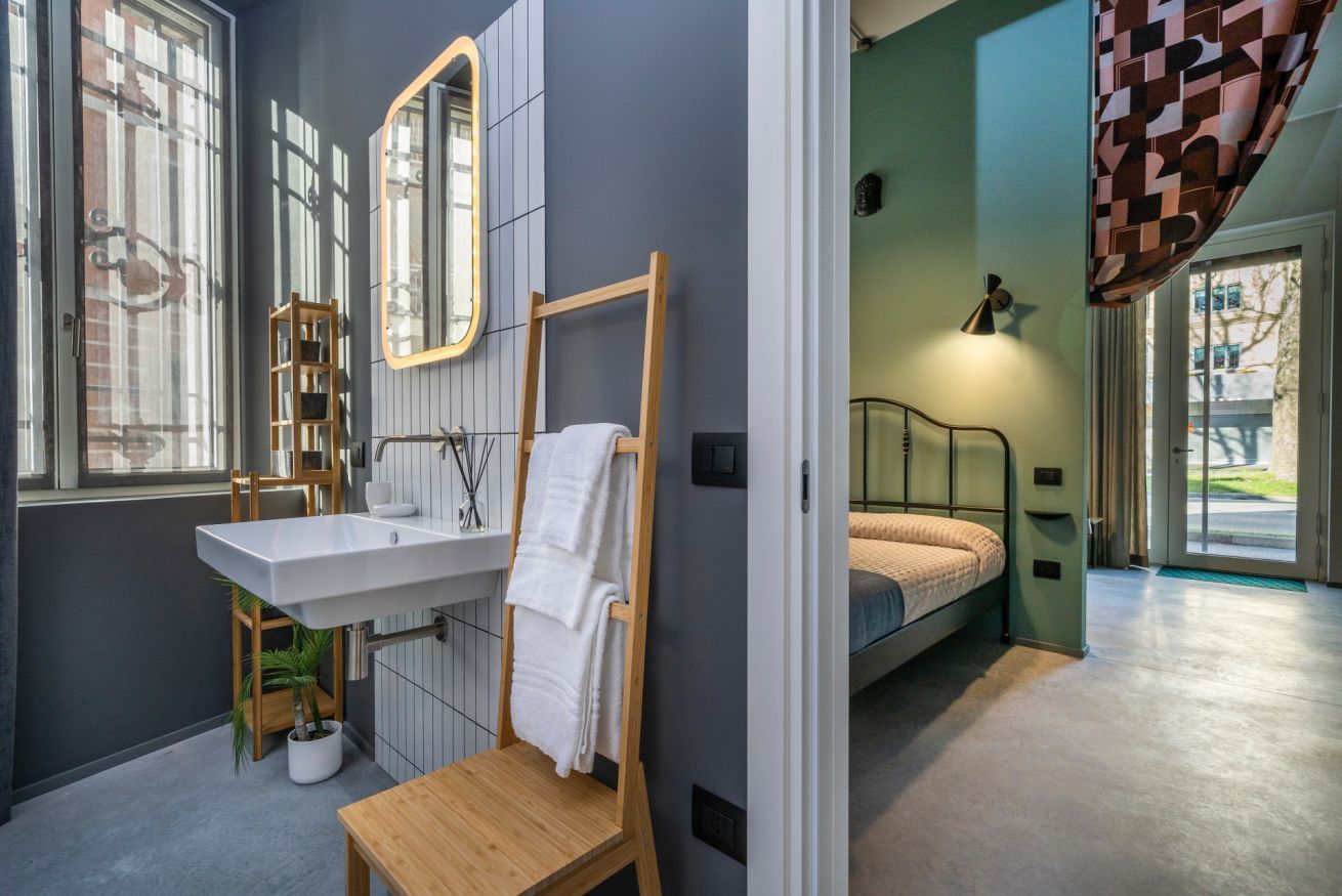 Une salle de bain moderne équipée d’un lavabo, d’un miroir, d’un porte-serviettes et d’une chaise en bois.