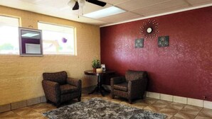A room with two armchairs, a small table with a plant, a rug, a ceiling fan, and a window with blinds. - Econo Lodge Mena near QueenWilhelmina State Park (Mena)