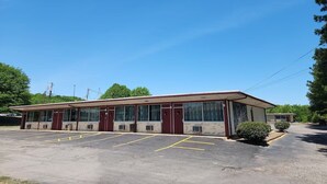 A motel with a row of rooms, a parking lot, and a small garden area. - Econo Lodge Mena near QueenWilhelmina State Park (Mena)