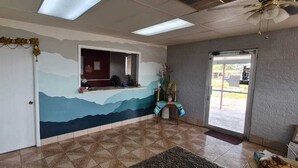 A reception area with a mural, a reception desk, and a door. - Econo Lodge Mena near QueenWilhelmina State Park (Mena)
