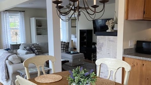 A dining area with a wooden table, white chairs, and a chandelier.