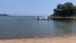 A sandy beach with a dock and sailboats.