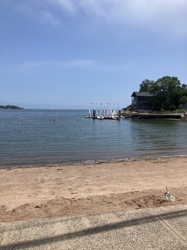 A sandy beach with a dock and sailboats.