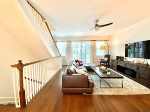 Relax in this inviting living area with a high ceiling, leather sofa, and flat-screen TV.